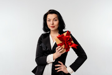 Fototapeta premium Beautiful smiling businesswoman holding gift box decorated with red ribbon. White background isolated studio portrait. Holidays, celebration and lifestyle concept