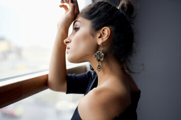 pretty woman near window posing attractive look earrings fashion model