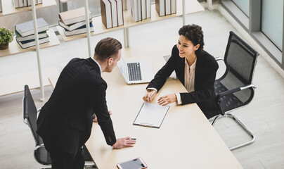 Millennial Caucasian successful thoughtful businessman and businesswoman colleague teamwork in formal suit working togeterh discuss brainstorming solution ideas at company workplace