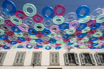multicolored and transparent buoys above an old street in the city of Carouge neighborhood of...