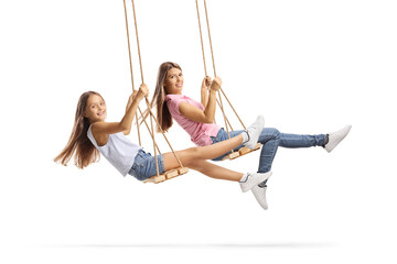 Young woman and a girl with long hairs swinging on wooden swings