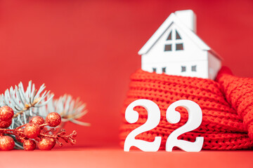 New Year 2022. White numbers 22 stand with toy house wrapped in red scarf and spruce branch. Merry Christmas. Copy space