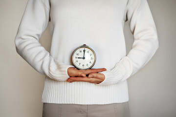 Time. Female hands holding vintage alarm clock with hands on the dial. Isolated on Gray background....