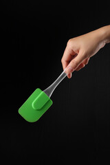 Hand holding cake spatula on black background