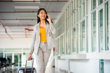 Businesswoman Dragging suitcase luggage bag, walking to passenger boarding in Airport. Woman travel...