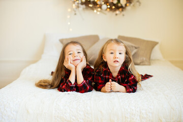 Two little sisters near the Christmas tree.