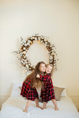 Two little sisters near the Christmas tree.