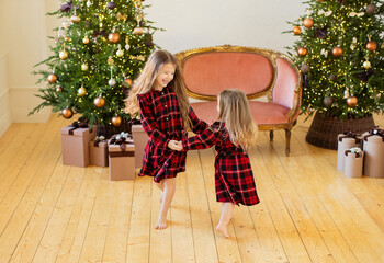 Two little sisters near the Christmas tree.
