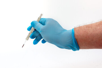 Man's hand in blue latex glove holding medical thermometer isolated on white background. Medical topic concept