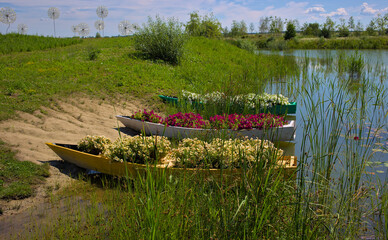 Lake with wooden boats decorated with flowers in the city park. A delightful landscape for relaxation. Landscaping in a well-kept park. Popular garden in Kyiv. Ukraine. Europe.