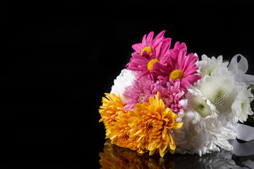 A bouquet of large multi-colored chrysanthemums on a black background with reflection.