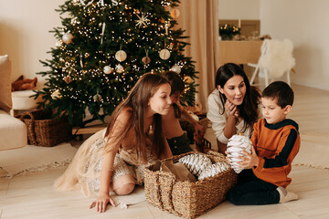 The concept of Christmas. A happy family with three children are preparing for the New Year holiday together decorating a Christmas tree in the cozy interior of the living room of the house in winter.