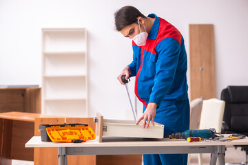 Young male carpenter working in the office during pandemic