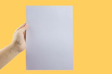 Hand holding blank cardboard on yellow background. with copy space