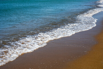 sea background surf with foam on sandy beach, horizontal