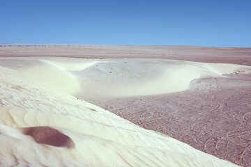 Lonely sand dunes in a strong wind under the sky against the background of arid desert