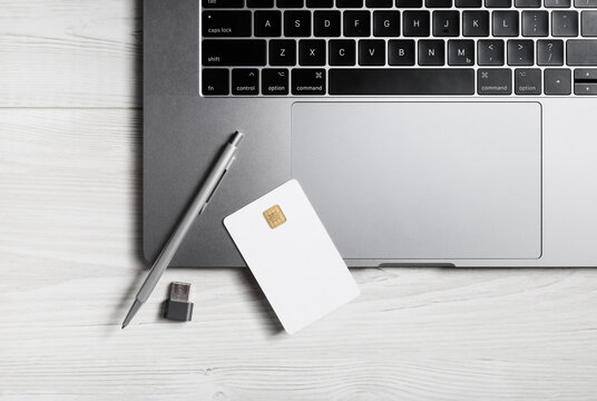 Online business concept. Blank bank card, pen, flash drive and laptop keyboard.