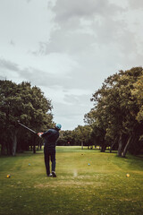 Man playing golf on a green field on a cloudy day