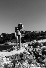 sporty woman in swimsuit on the rocky beach. black and white vertical