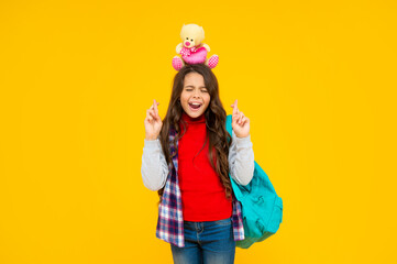 Fototapeta na wymiar glad kid has long curly hair carry school backpack hold toy on yellow background, school