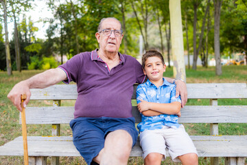 Fototapeta na wymiar Grandfather and his grandson sitting on a bench in the park