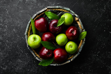 Set of red and green apples on a tray. Rustic style. On a black stone background.