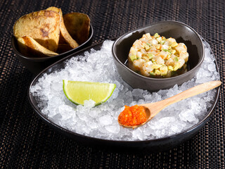 fresh scallop tartare, raw chopped scallop with avocado and caviar of flying fish tobiko in a bowl on ice bed