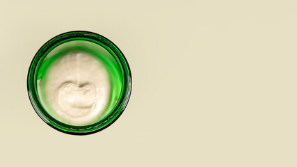 Body cream or face cream in a green jar on a green background. The concept of freshness and naturalness of cosmetics