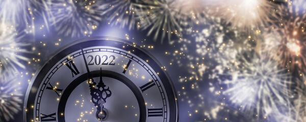 fireworks around the countdown clock 2022 at midnight, cheerful new year's eve party with...