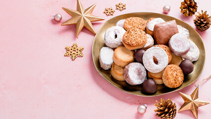 Fototapeta na wymiar Holiday delicacies polvorones and mantecados in golden plate on pink table overhead