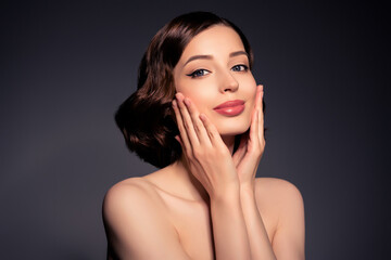 Naklejka premium Photo of smiling beautiful good looking female touch cheeks apply moisturizing cream isolated on black color background