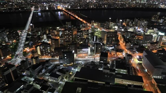 Aerial view time lapse of Osaka City central business downtown and Yodo River with its bridges at night. Osaka Skyline from Floating Garden Observatory Umeda Sky Building, Japan, reflect in the glass.