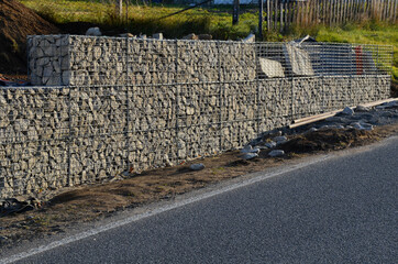 construction of a gabion retaining wall, as part of the house fencing. workers put geotextiles and...