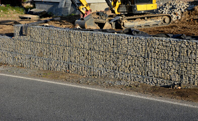 construction of a gabion retaining wall, as part of the house fencing. workers put geotextiles and...