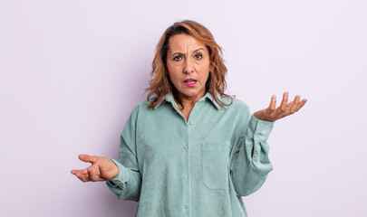 middle age woman shrugging with a dumb, crazy, confused, puzzled expression, feeling annoyed and...