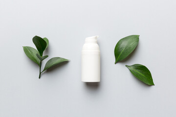 Organic cosmetic product with green leaves on color background. Flat lay