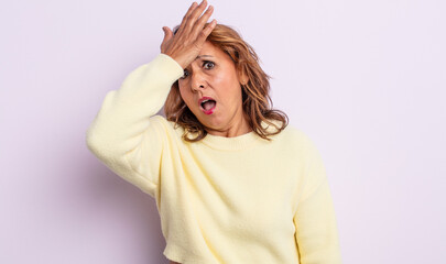 middle age woman raising palm to forehead thinking oops, after making a stupid mistake or...