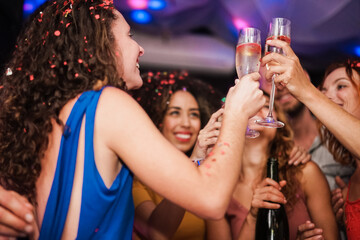 Group of happy friends cheering with champagne at private party - Focus on right hand holding glass
