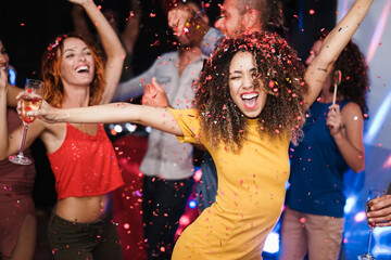 Young multiracial people dancing and celebrating with champagne at party night club for 2022 new...