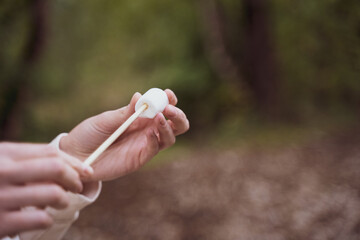 The person strings marshmallows on a stick. Fun in the camp