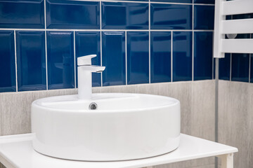 Naklejka na ściany i meble Faucet for water and white separate high sink on stone pedestal with blue ceramic tile. Loft style bathroom