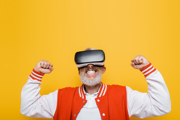 middle aged man in bomber jacket and vr headset rejoicing isolated on yellow