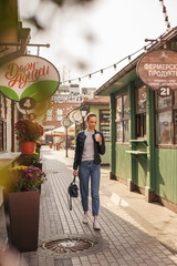 Obraz premium A girl walks through the central streets of the city drinking coffee.