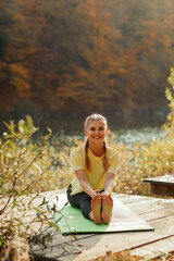 A young beautiful blonde woman does yoga in nature