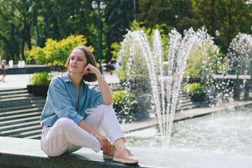 Urban portrait of young attractive business woman in eye glasses and casual clothes. Woman walking in the city street, green park, reading a book, relax, works in sunny day.