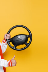 cropped view of middle aged man holding steering wheel and showing like on yellow