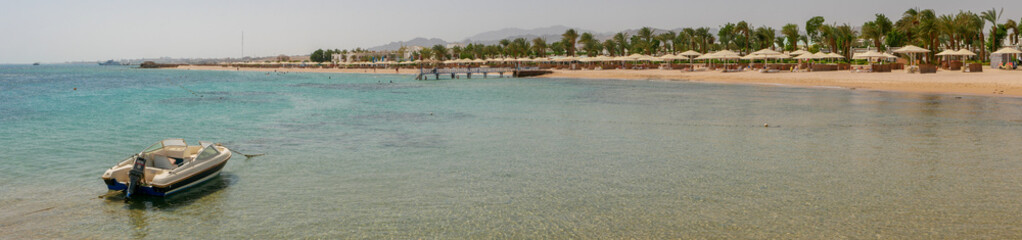 Fototapeta na wymiar Hurghada, Egypt - September 22, 2021: Panoramic view from the motor boat and the coast of the red sea. People are relaxing and swimming on the sandy beach.
