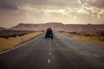 The car drives along the road leading through the Black and White Desert in Bahariya. Egypt