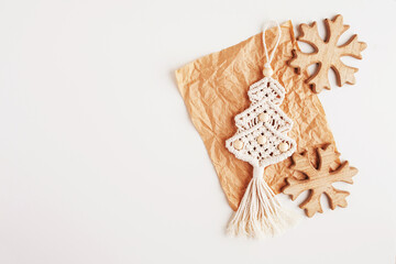 Christmas macrame decor. Christmas tree and wooden snowflakes on craft paper, white background. Natural materials - cotton thread, wood beads. Eco decorations, ornaments, hand made decor. 