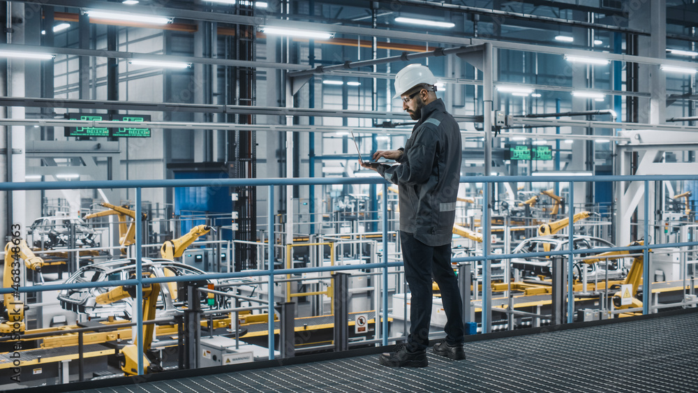 Aufkleber Car Factory Engineer in Work Uniform Using Laptop Computer. Automotive Industrial Manufacturing Facility Working on Vehicle Production with Robotic Arms Technology. Automated Assembly Plant.
